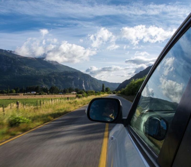 car-driving-down-road-with-mountains-in-background